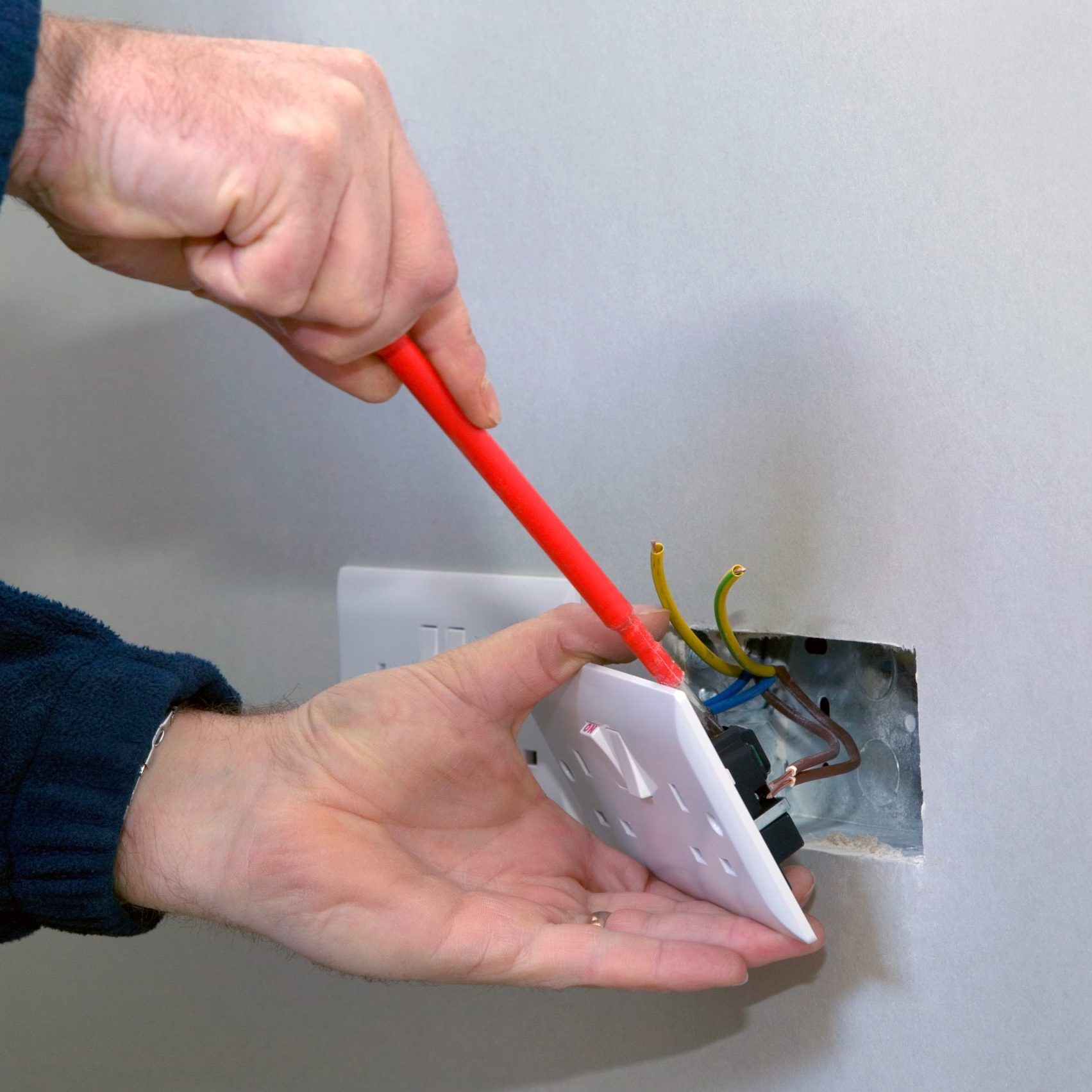 The hands of an electrician installing a power socket